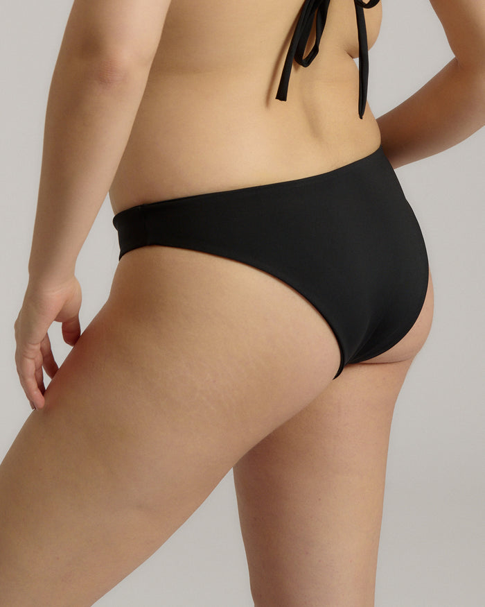 Person wearing a black bikini bottom against a neutral background