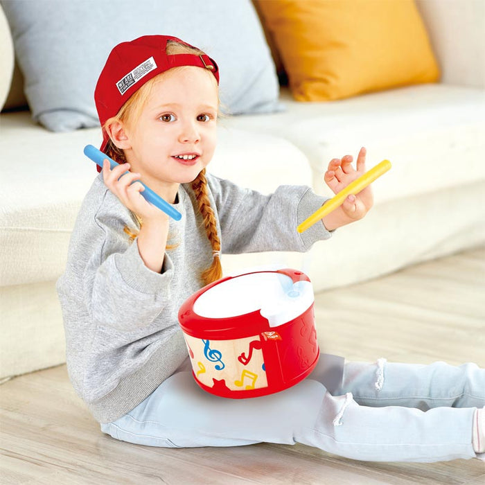 Child playing with a toy drum set on a light-colored couch.
