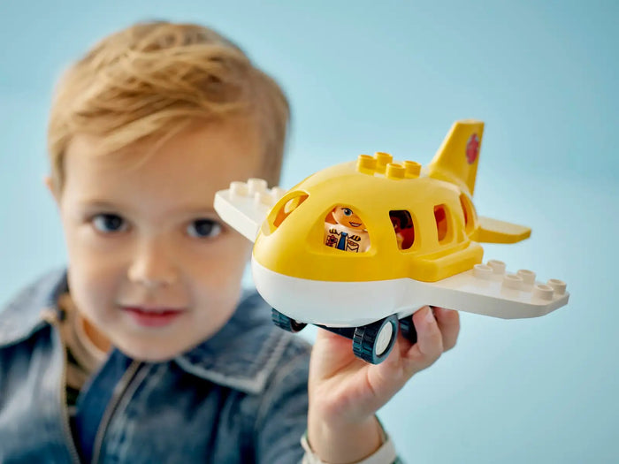 Child holding a toy airplane against a light blue background