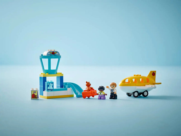 Toy set with a building block tower, airplane, and figures on a light blue background
