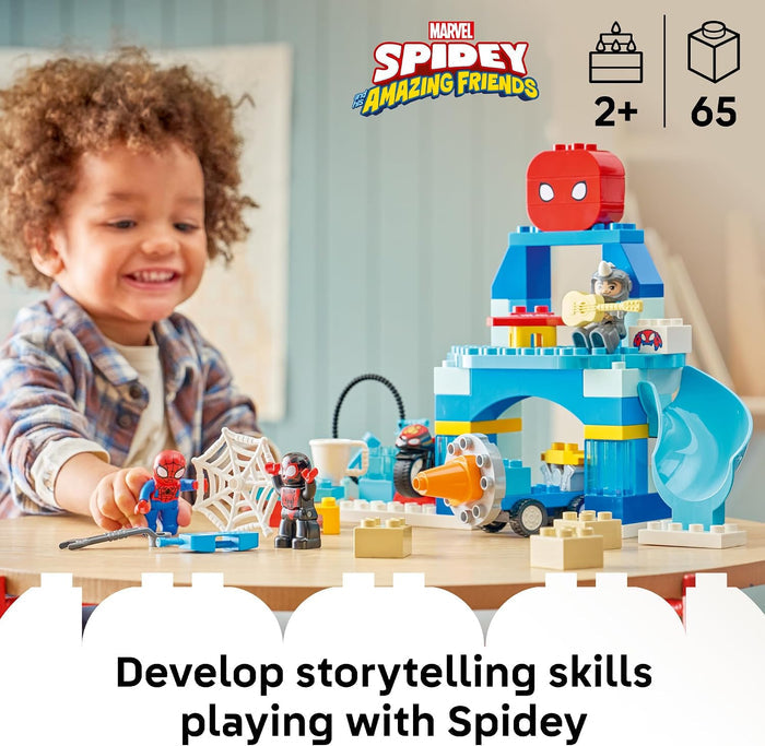 A young child smiling at a table with a LEGO Marvel Spidey - The Amazing Friends building set. The set includes a blue and white castle structure, a red Spider-Gwen figure, Spider-Man and Black Cat minifigures, and other small building pieces.