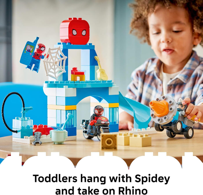 A toddler is playing with a Spider-Man themed toy set featuring a blue and white castle-like structure, a red Spider-Man head piece, web details, and a small vehicle, with a text overlay at the bottom.