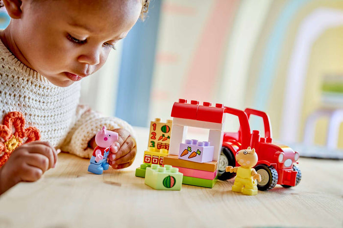 Child playing with colorful toy blocks and figures on a wooden surface.