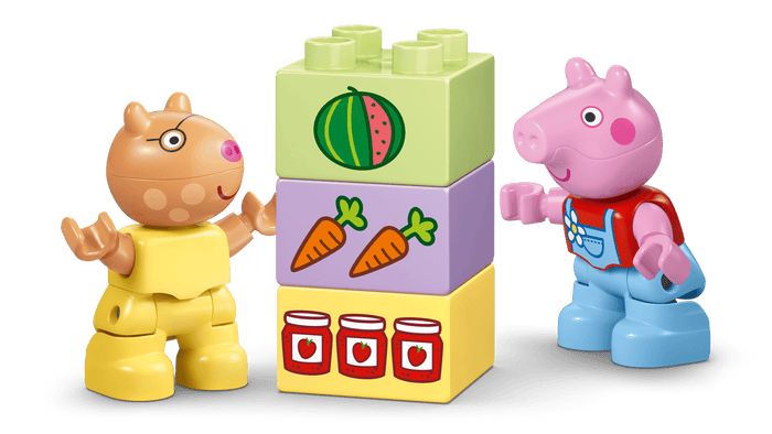 Two toy figures, one resembling a pig and the other a bear, standing next to a colorful block with illustrations on a green background.