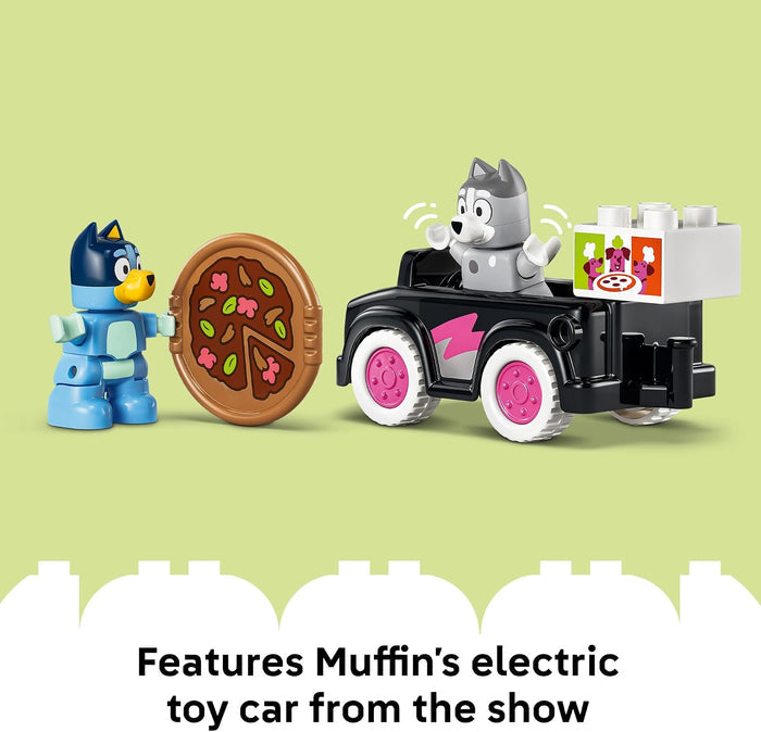 Toy figures of a blue character with a pizza, a gray character in an electric toy car, on a light green background.