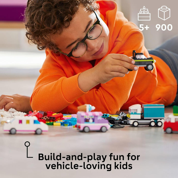 Child playing with toy cars and trucks on a table, surrounded by building blocks.