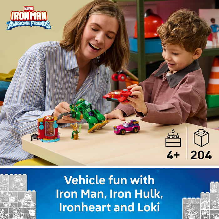 A woman and a young boy play with a LEGO Iron Man and Friends set at a light wood table. The set includes a green Iron Hulk vehicle, a red Iron Man vehicle, and a pink car.