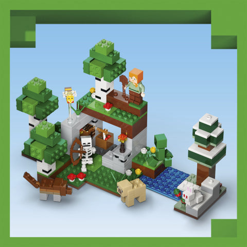 A block-style toy building set showing a small house, trees, animals, flowers, and a figure, assembled on a light blue background with a green decorative border.