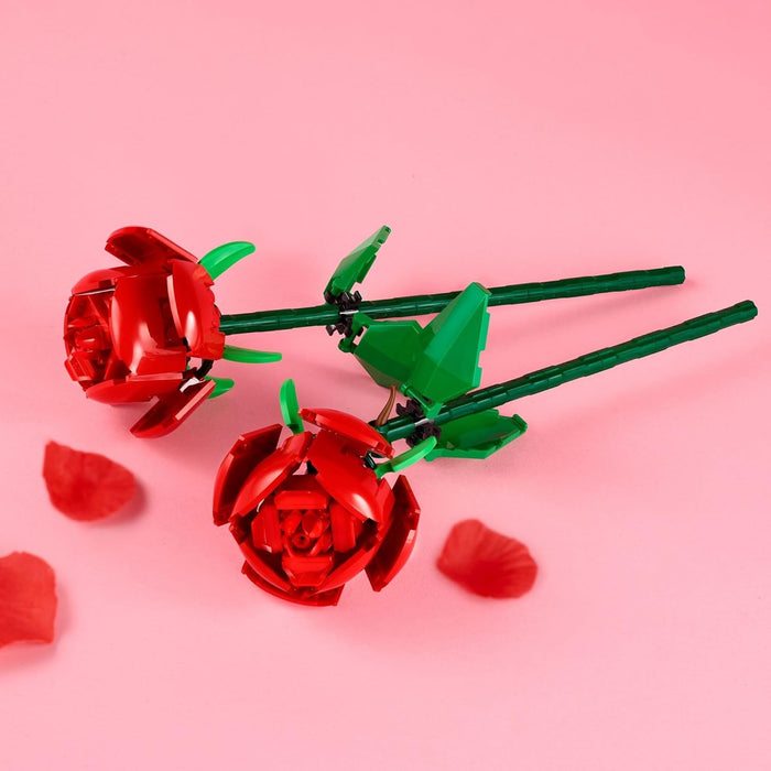 Red rose-shaped objects with green stems on a pink background