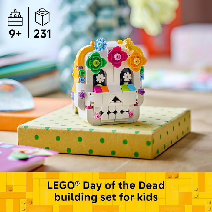 LEGO Day of the Dead building set for kids, featuring a white skull model decorated with colorful flowers and patterned details, displayed on a yellow gift box with green polka dots. The image includes LEGO branding and age information.