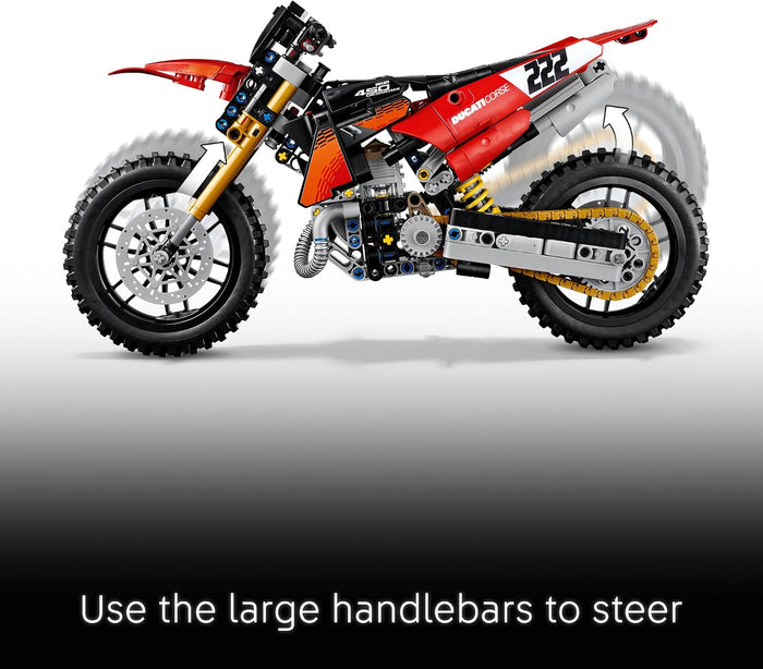 A red and black toy motocross bike model with gold and silver mechanical details, shown in profile on a white-to-gray gradient background with a black banner at the bottom containing the text 'Use the large handlebars to steer'.