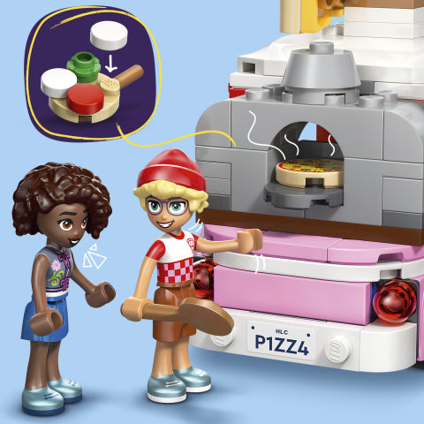 A toy building-block set showing a pink and gray pizza oven with a pizza inside, alongside two child-like figures holding wooden pizza pincers. An inset circle at the top left shows a close-up of the pizza topping pieces.