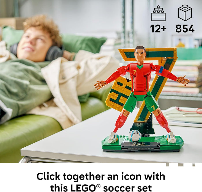 Toy figure on a table with a person lying on a couch in the background, featuring LEGO branding.