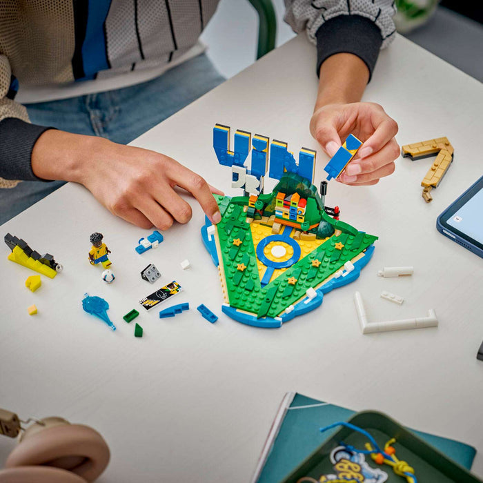 Children playing with a LEGO set on a table with a tablet displaying a design.