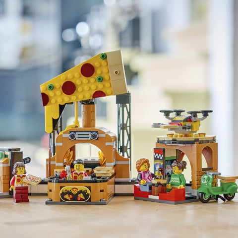LEGO set with a pizza stand and people figures on a blurred indoor background