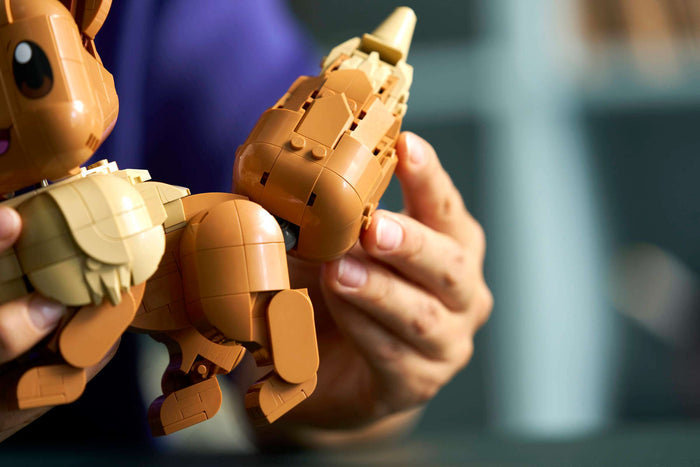 Close-up of hands holding a partially assembled toy figure with a blurred background