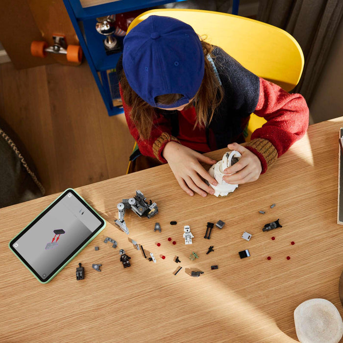 Person working on a small model or craft project at a table with various items including a smartphone.