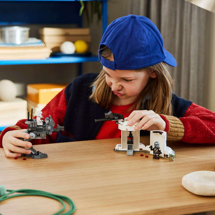 Child playing with toy building sets on a table in a room with shelves in the background