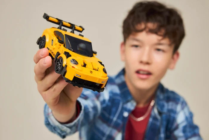 Child holding a yellow toy car against a plain background