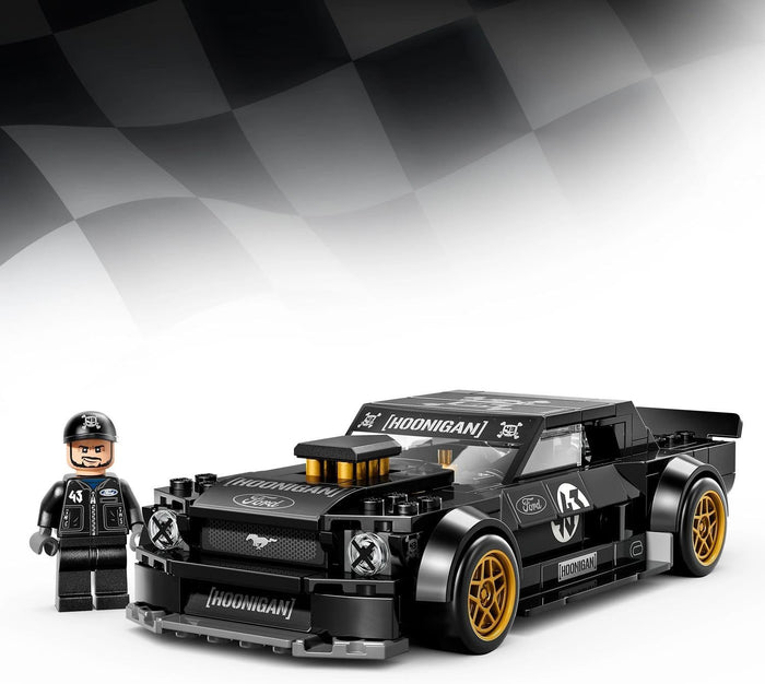 A black racing car building block set with a small driver minifigure, shown on a white background with a black-and-white checkered flag graphic behind it. The car has gold wheels and multiple white and black decals, including 'MooNigan' and Ford branding.
