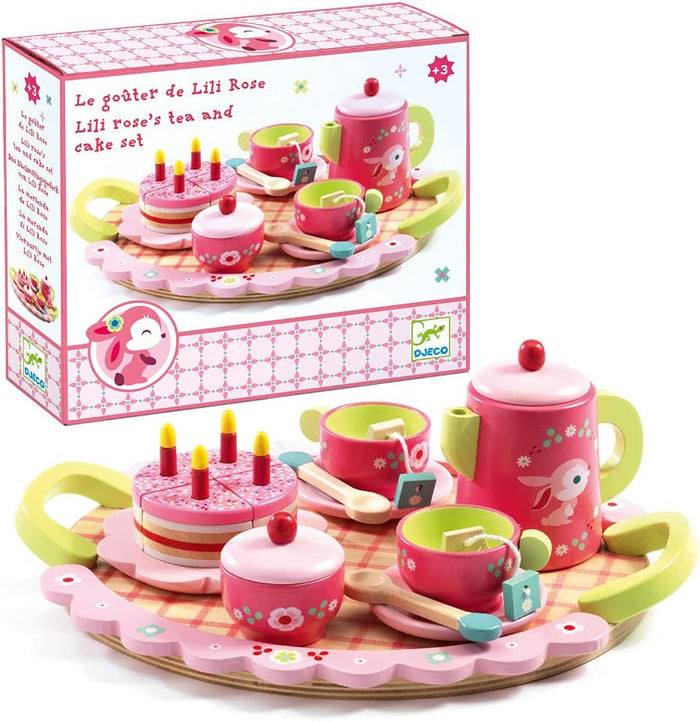 Toy tea set with pink and green colors, including cups, teapot, and cake, in front of its packaging.