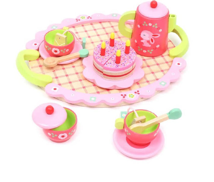 Pink, yellow, lime green wooden tea set with a colorful cake with four candles on a white background