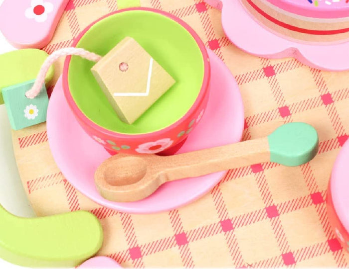 Pink and lime green wooden tea cup with wooden spoon on a table with a checkered pattern table cloth