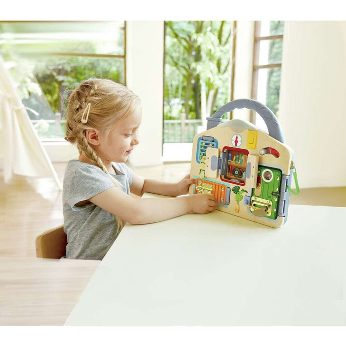 Child playing with the Lock and Learn Playboard on a white table near windows