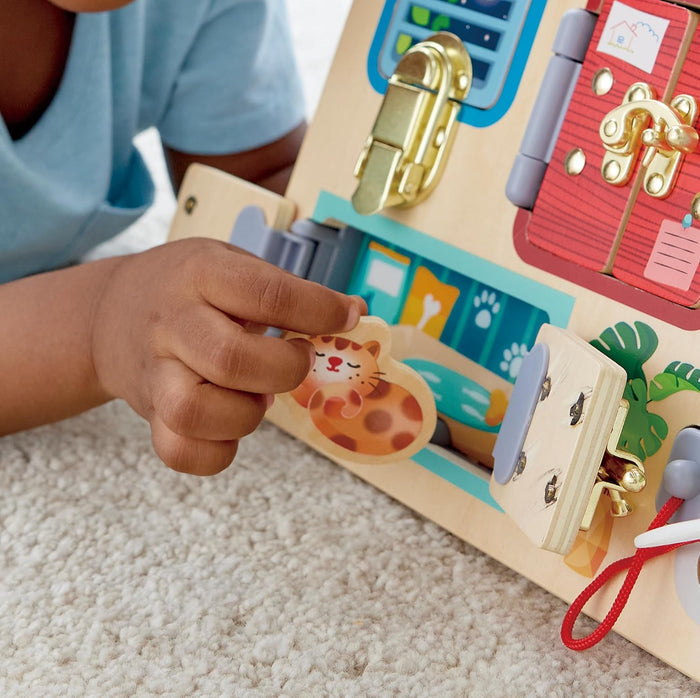 Close up of the Lock and Learn Playboard with two small doors open and a child holding a tiny wooden kitty.