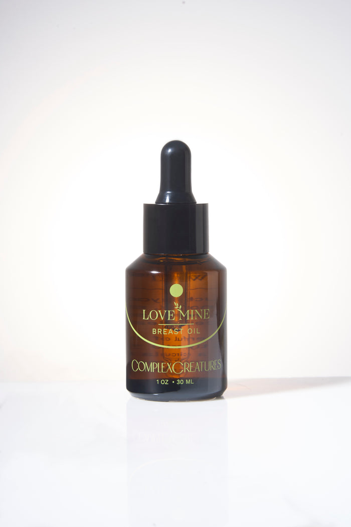 A bottle of Love Mine Breast Oil with a dropper cap, labeled with the brand Complex Creatures.