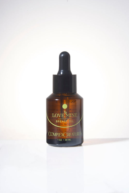 A bottle of Love Mine Breast Oil with a dropper cap, labeled with the brand Complex Creatures.