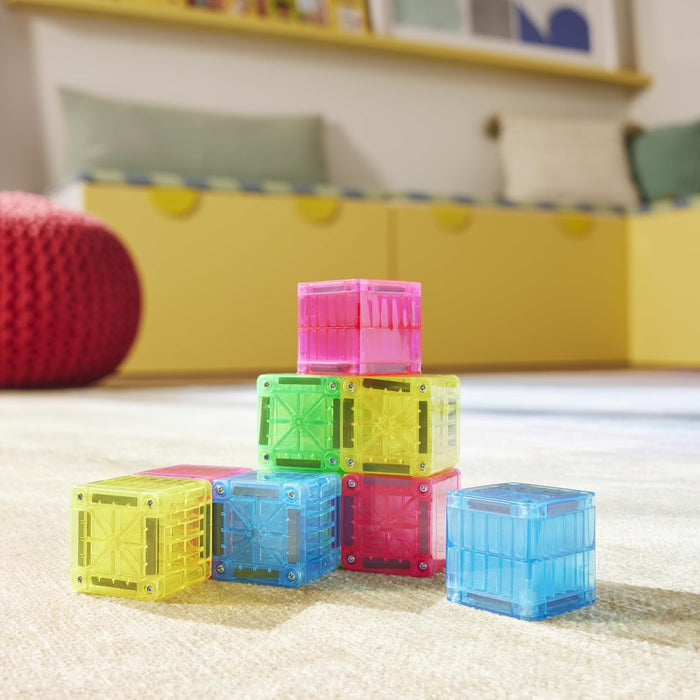 Blue, yellow, red, green and pink Magna Tile Cubes stacked on a white carpet in a playroom.