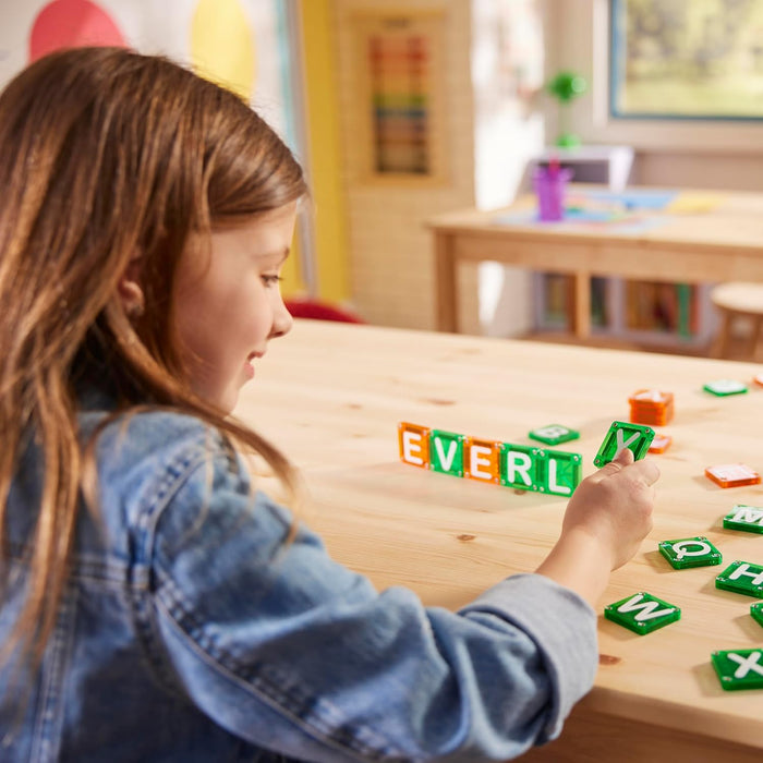 Child connecting letter tiles together to make words on a wooden table
