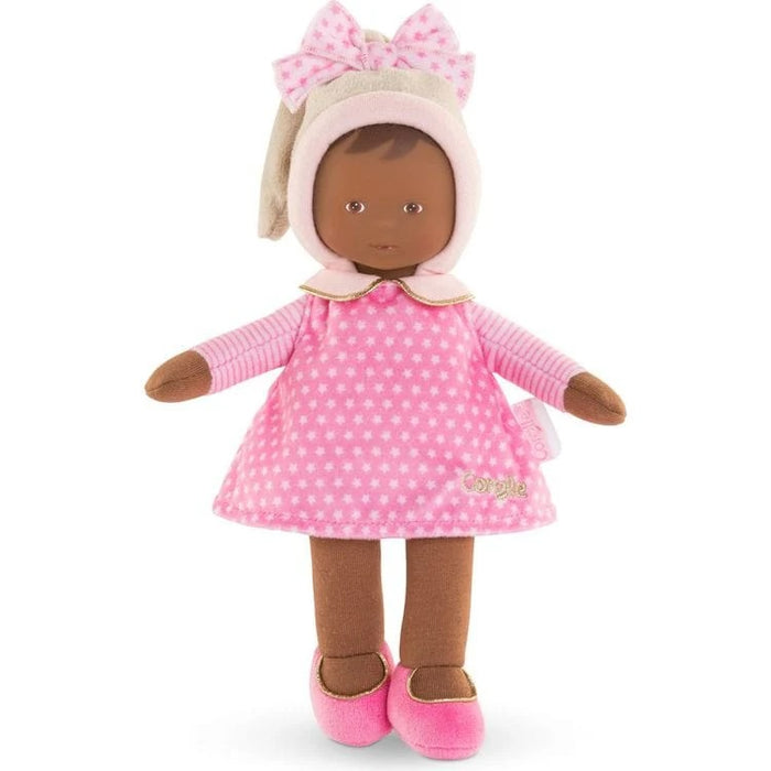 A small, soft baby doll with a pink dress, stocking cap, and shoes. The doll has a sweet, realistic vinyl face and is designed for tiny hands to hold.