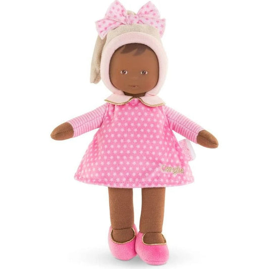 A small, soft baby doll with a pink dress, stocking cap, and shoes. The doll has a sweet, realistic vinyl face and is designed for tiny hands to hold.