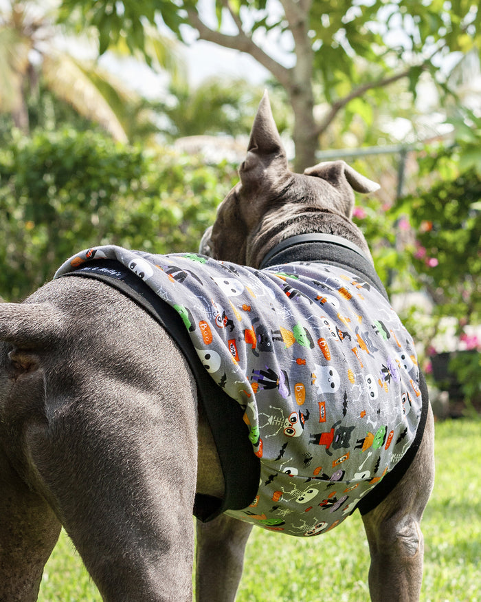 Back profile of a gray pitbull modeling the monster squad Halloween Dog Muscle Tank adorned with a playful print of iconic monsters like Dracula and Frankensteins accented with black trim.