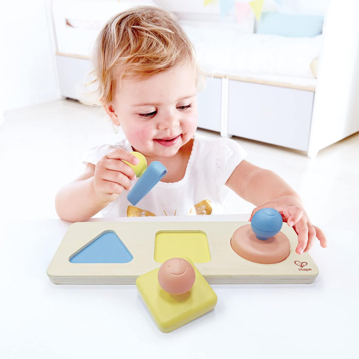 Child playing with a shape sorting toy on a white surface