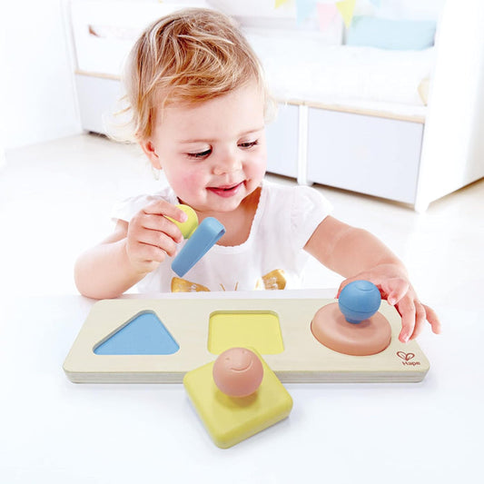 Child playing with a shape sorting toy on a white surface