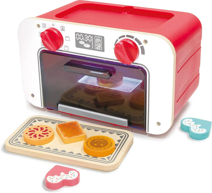 Toy oven with a tray of cookies and cookie cutters on a white background