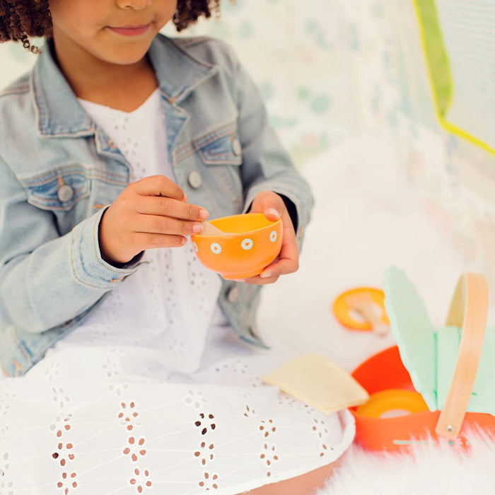 Child playing with an orange picnic bowl on a white background