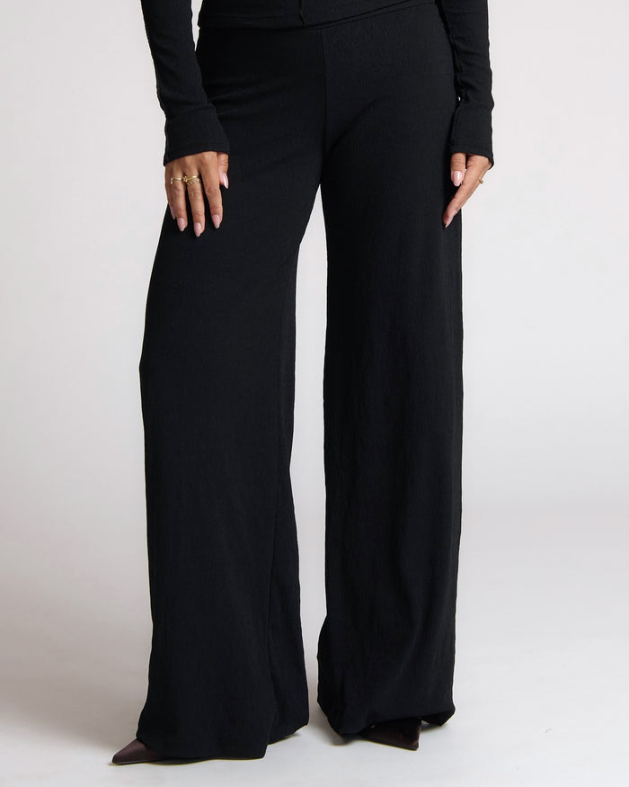 Black wide-leg pants worn by a person on a white background