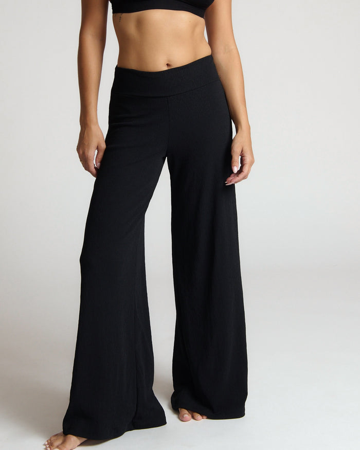 Person wearing black wide-leg pants on a plain background