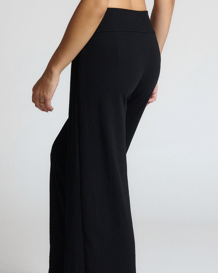 Black high-waisted pants on a plain background