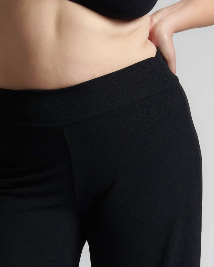 Person wearing black pants against a neutral background