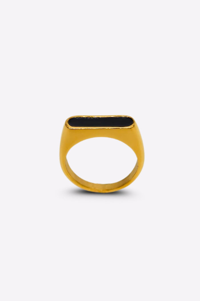 Front view of a gold ring featuring a raised oblong black enamel setting that serves as its centerpiece.