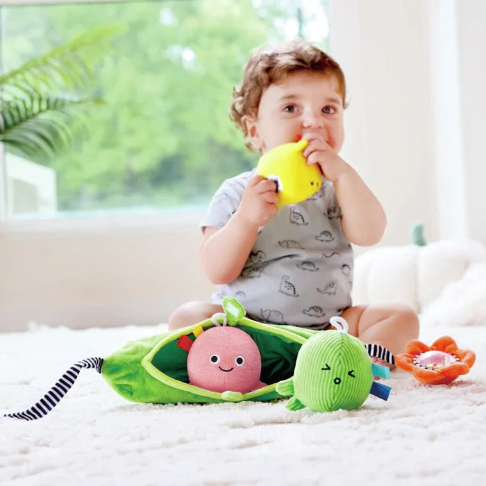 Child sitting on a bed with toys, holding a yellow toy.