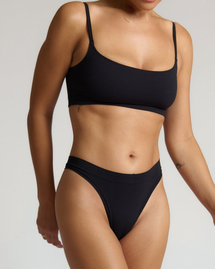 Person wearing a black bra set on a neutral background