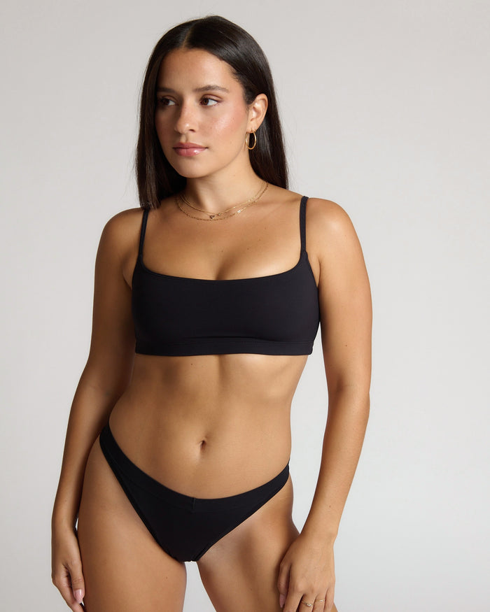 Woman wearing a black bra against a plain background