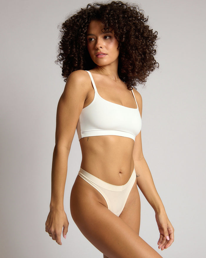 Woman wearing a white cropped cami on a plain background