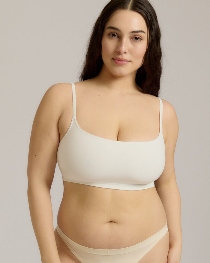 Woman wearing a white bra and white underwear on a plain background